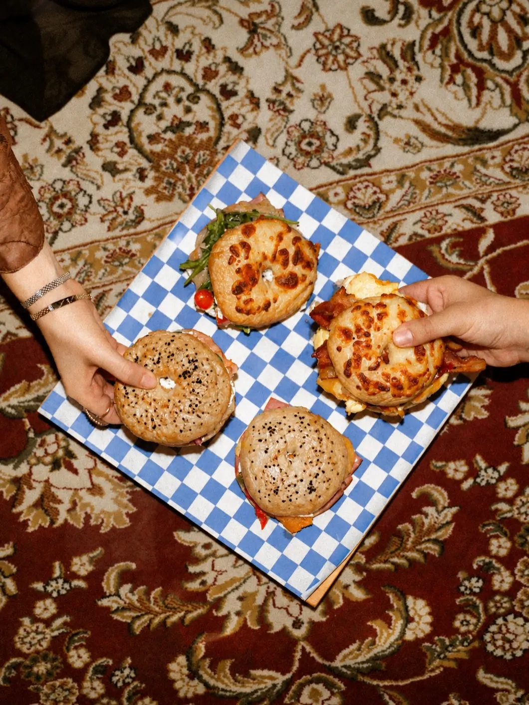 Cuatro bagels del Gran Banquete sobre papel a cuadros azules, vistos desde arriba